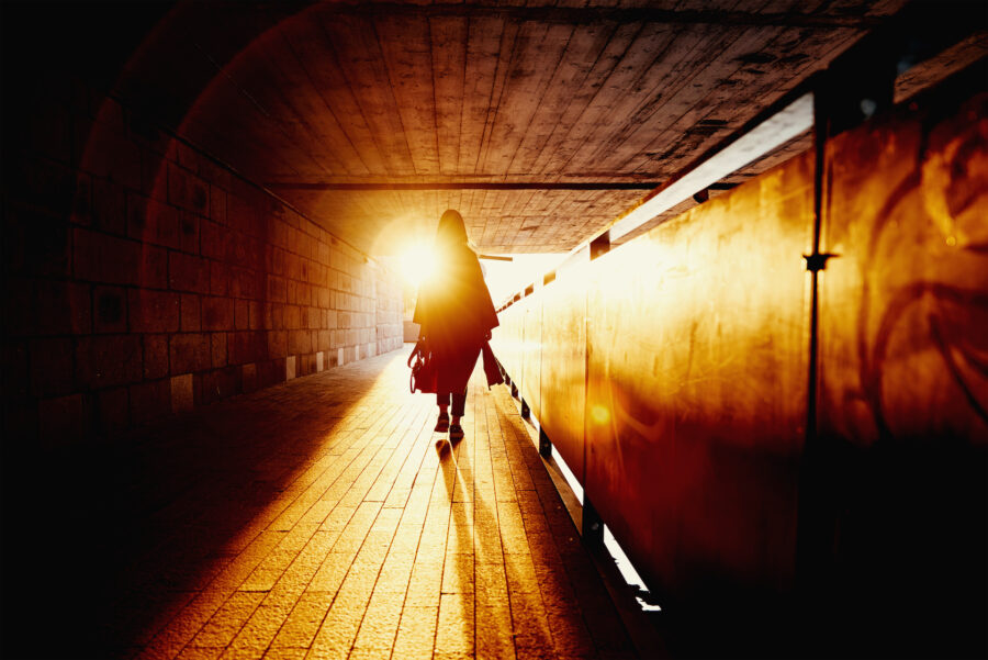 Woman silhouette at tunnel with sun rays